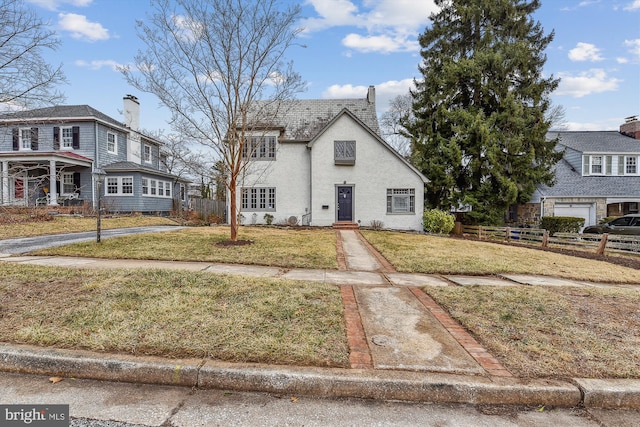 view of front facade featuring a chimney, fence, and a front lawn