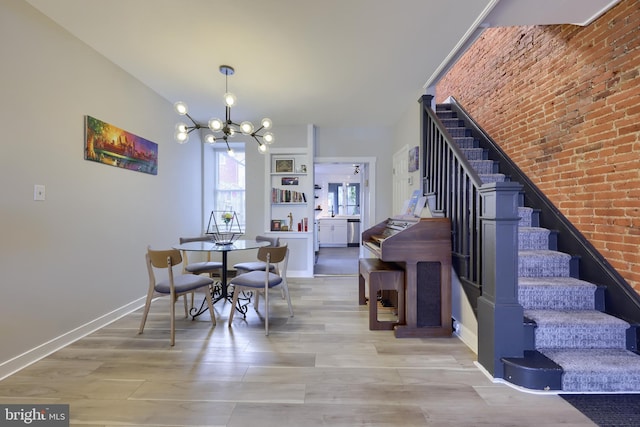 dining area featuring light wood-type flooring, an inviting chandelier, stairs, and baseboards