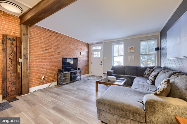 living area with beam ceiling, light wood-style flooring, and brick wall