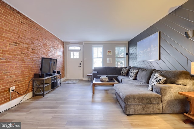 living area featuring brick wall, wood walls, light wood-type flooring, and an accent wall