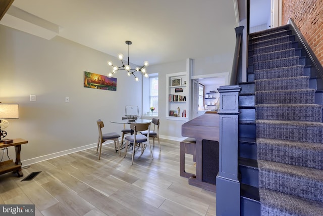 dining space featuring visible vents, light wood-style flooring, an inviting chandelier, baseboards, and stairs