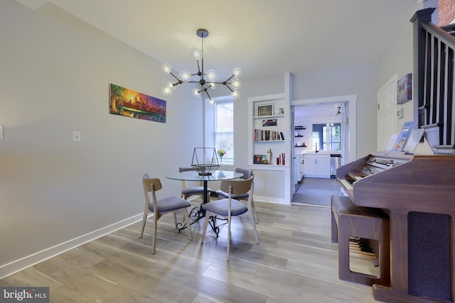 dining room featuring a chandelier, light wood-type flooring, and baseboards