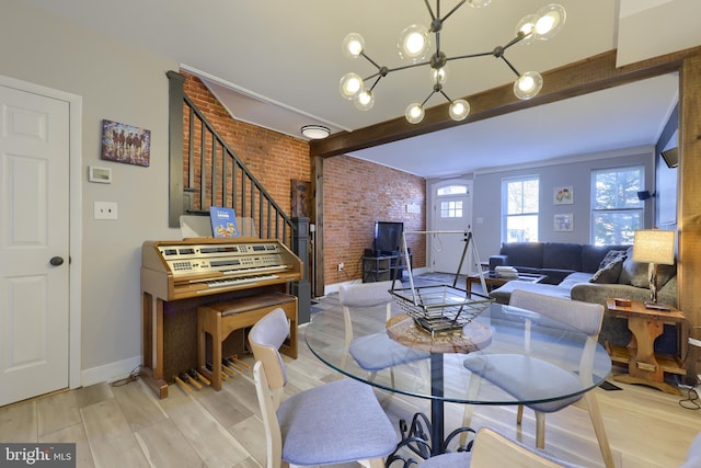 dining space featuring beam ceiling, stairway, brick wall, light wood-type flooring, and baseboards