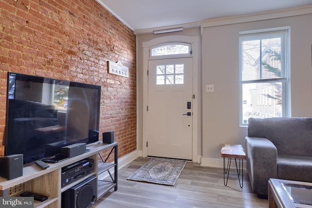 foyer featuring light wood-type flooring, baseboards, and brick wall