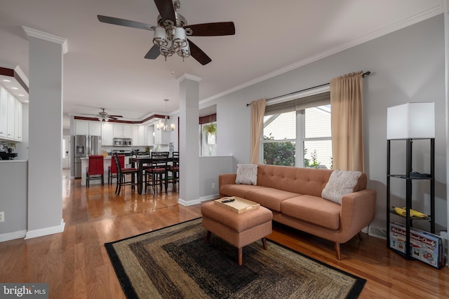 living room featuring ornamental molding, ceiling fan with notable chandelier, and light hardwood / wood-style flooring