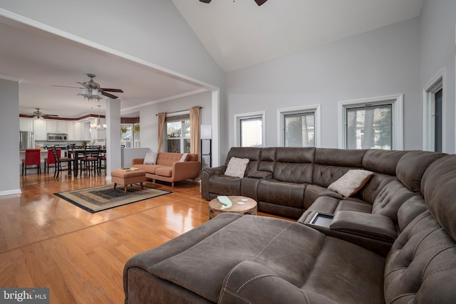 living room featuring crown molding, ceiling fan with notable chandelier, light hardwood / wood-style flooring, and high vaulted ceiling