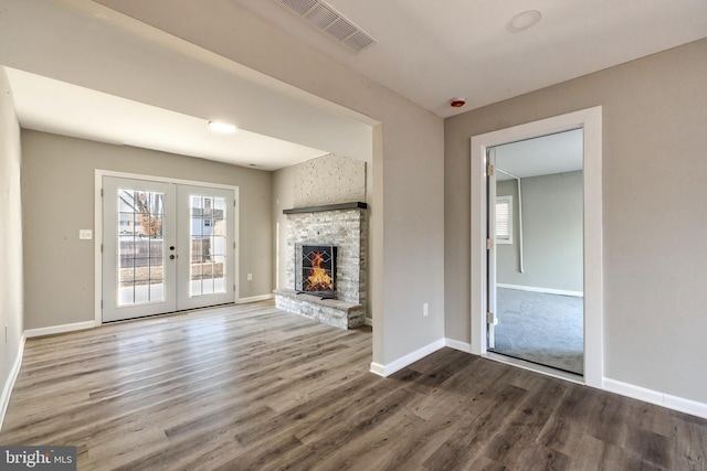 unfurnished living room featuring hardwood / wood-style floors, a fireplace, and french doors