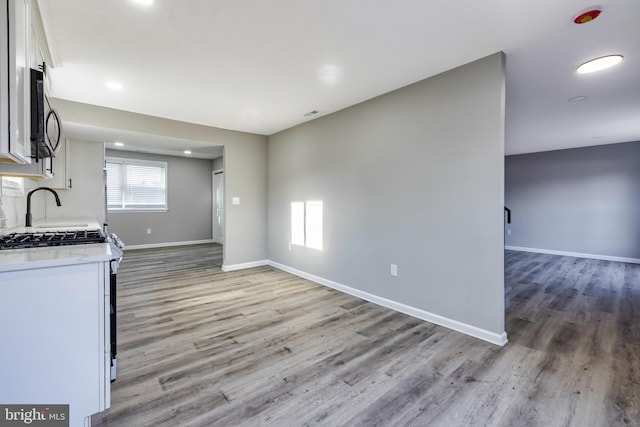 kitchen featuring light hardwood / wood-style flooring, white cabinets, and white gas range oven