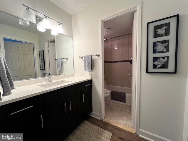 bathroom featuring shower / bathing tub combination, toilet, vanity, wood finished floors, and baseboards