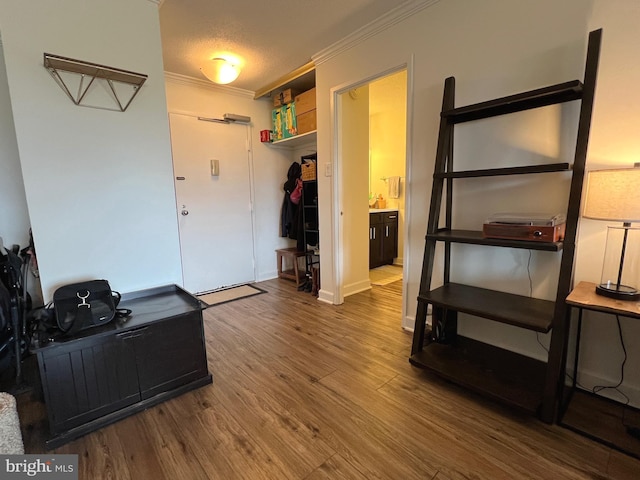 interior space featuring a textured ceiling, baseboards, wood finished floors, and crown molding