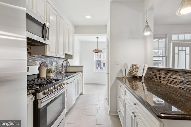 kitchen featuring appliances with stainless steel finishes, decorative light fixtures, sink, and white cabinets