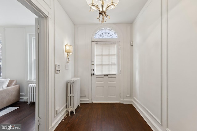 doorway to outside with a chandelier, dark hardwood / wood-style floors, and radiator