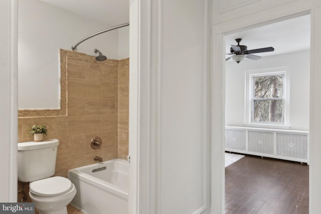 bathroom with radiator, tile walls, hardwood / wood-style floors, tiled shower / bath, and toilet