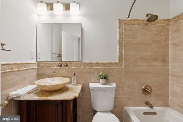 full bathroom featuring vanity, tile walls, toilet, and tiled shower / bath