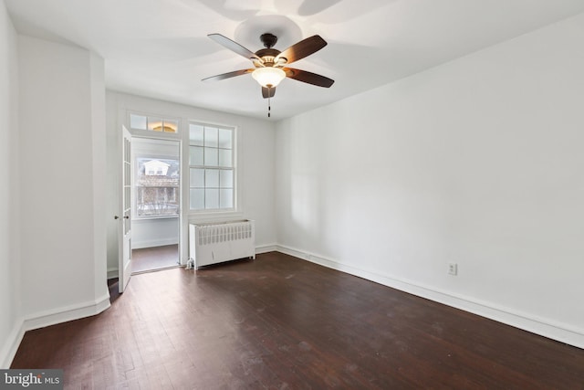 empty room with dark wood-type flooring, ceiling fan, and radiator