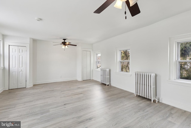 unfurnished room featuring ceiling fan, radiator heating unit, and light wood-type flooring