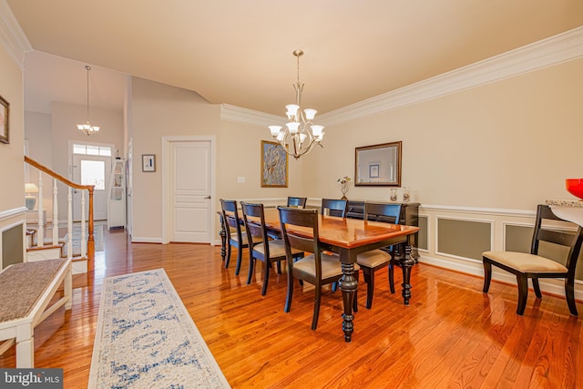 dining area with hardwood / wood-style floors, crown molding, and a chandelier