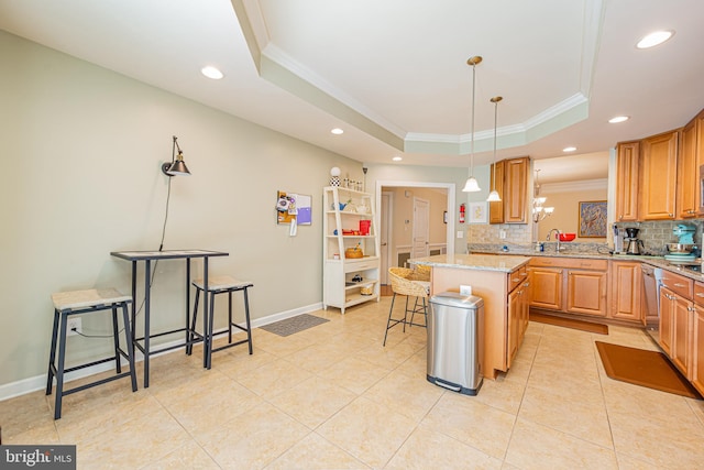 kitchen featuring a breakfast bar, hanging light fixtures, a center island, light stone counters, and a tray ceiling