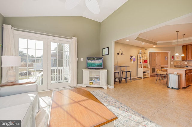 living room featuring light tile patterned flooring, lofted ceiling, ceiling fan, a raised ceiling, and crown molding