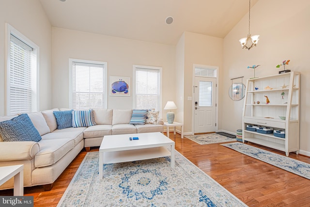 living room with hardwood / wood-style flooring, vaulted ceiling, and an inviting chandelier