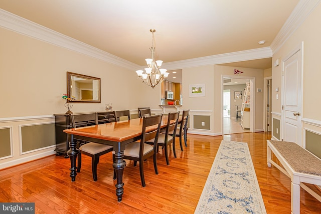 dining area with ornamental molding, a chandelier, and light hardwood / wood-style flooring