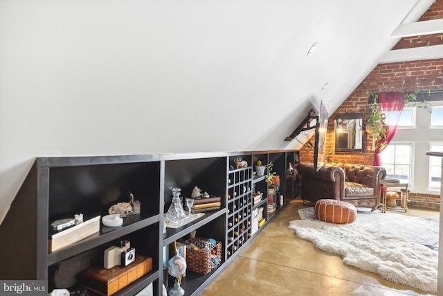 interior space featuring lofted ceiling, concrete flooring, and brick wall