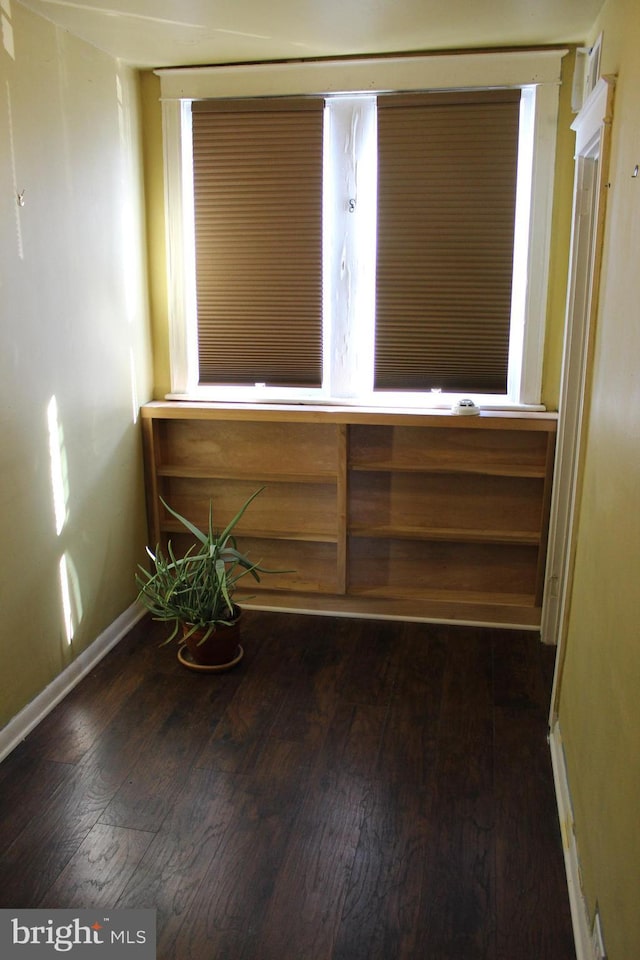 empty room with baseboards and dark wood-type flooring