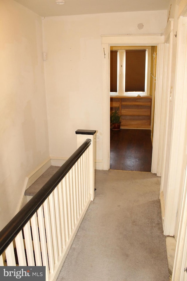 hallway with carpet flooring and an upstairs landing