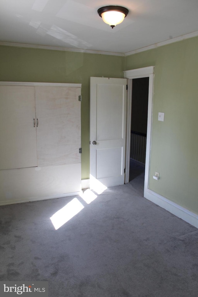 unfurnished bedroom featuring baseboards, carpet floors, and ornamental molding