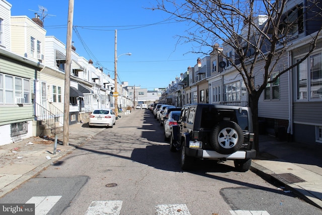 view of road featuring sidewalks, curbs, a residential view, and street lights