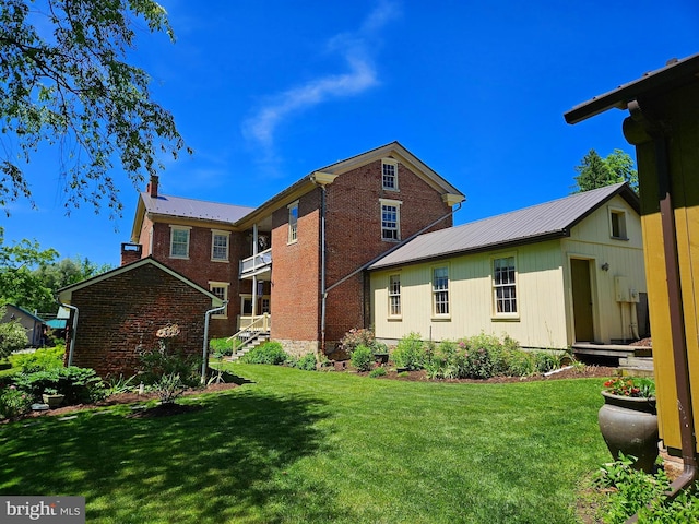 rear view of property featuring a balcony and a yard