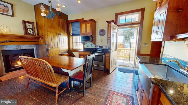 dining space with an inviting chandelier, dark wood-type flooring, sink, and a fireplace