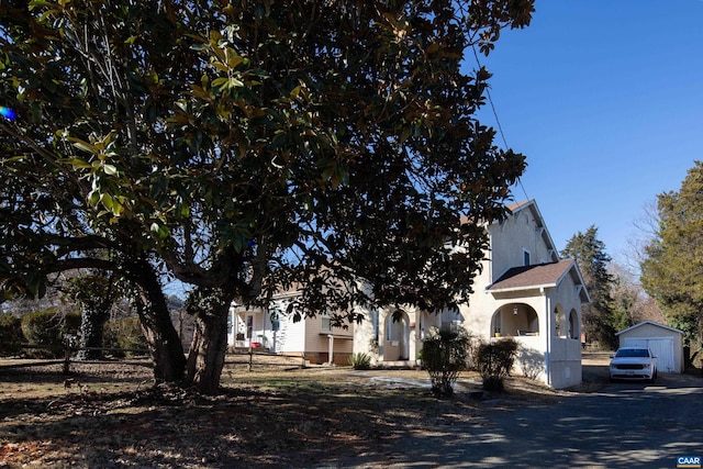 view of property hidden behind natural elements featuring a garage and an outdoor structure