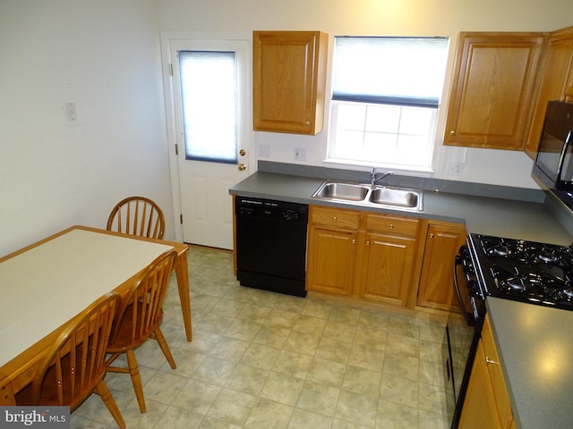 kitchen with black appliances, brown cabinetry, dark countertops, and a sink