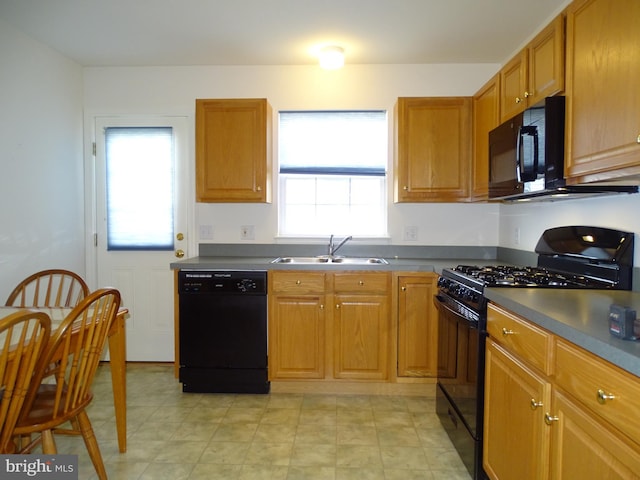 kitchen featuring black appliances, dark countertops, a sink, and brown cabinets