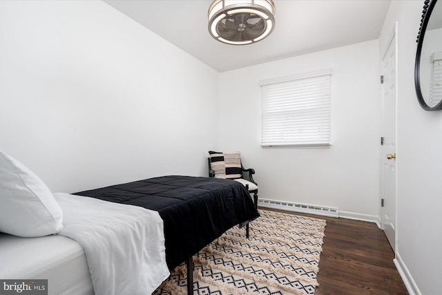 bedroom with dark hardwood / wood-style floors and baseboard heating