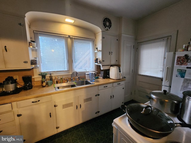 kitchen with white cabinetry, sink, butcher block counters, and white refrigerator