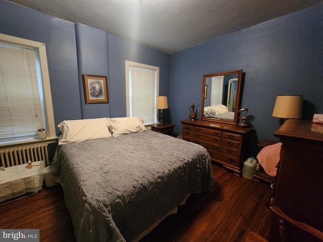 bedroom with dark hardwood / wood-style floors and radiator