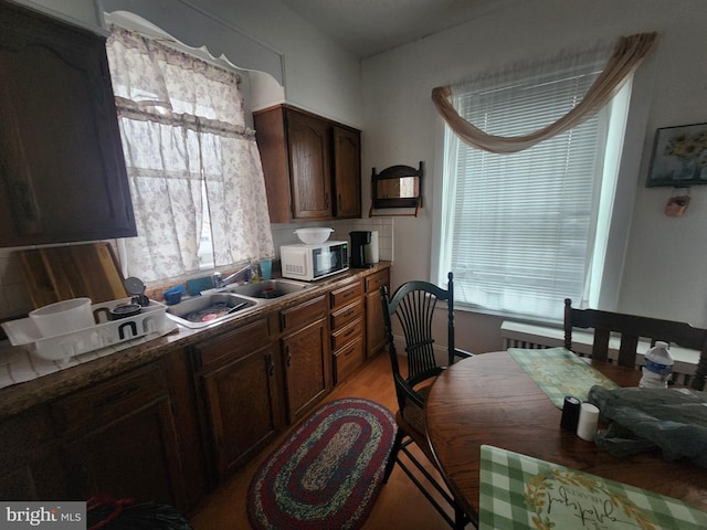 kitchen featuring tasteful backsplash, dark brown cabinets, sink, and light hardwood / wood-style flooring