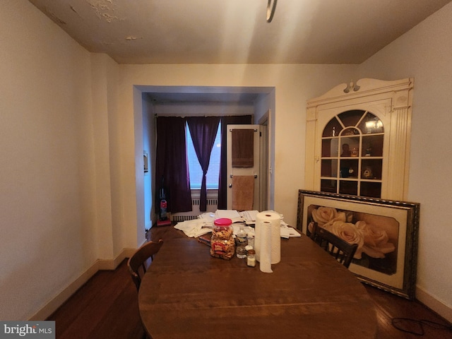 dining space with dark wood-type flooring and radiator heating unit