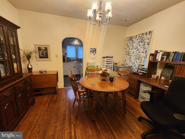 dining area featuring dark wood-type flooring, a chandelier, and sink