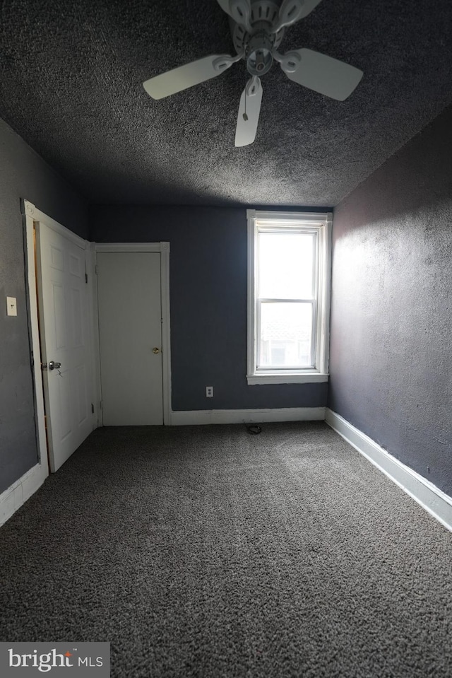 carpeted empty room with ceiling fan and a textured ceiling