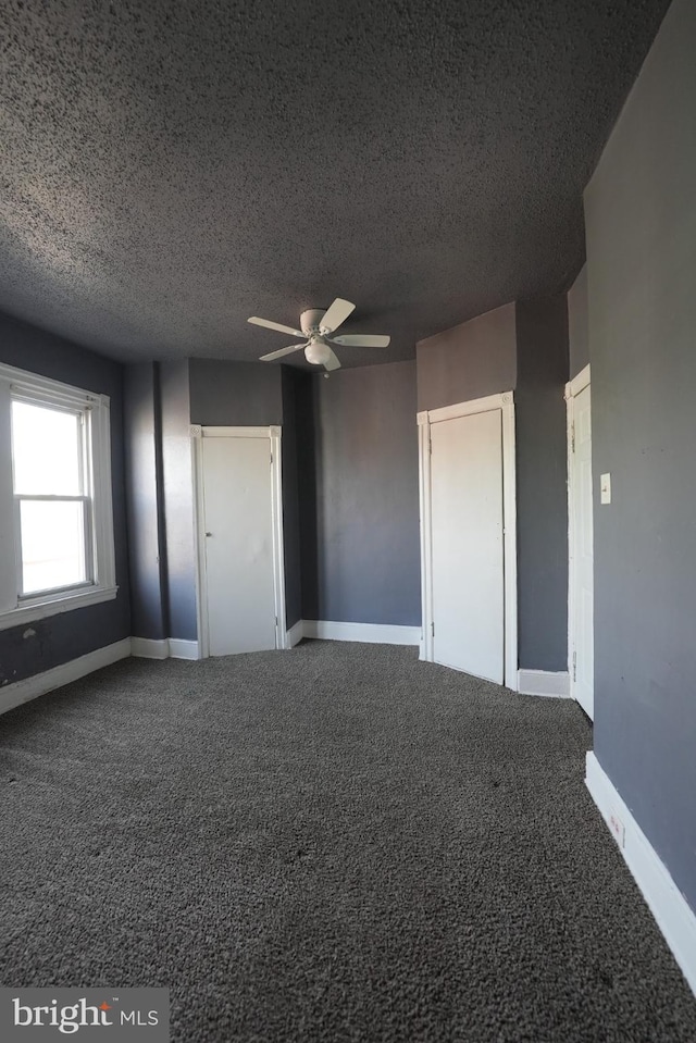 interior space featuring ceiling fan, carpet floors, and a textured ceiling