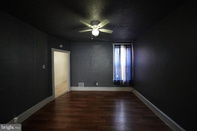 spare room with dark wood-type flooring, ceiling fan, and a textured ceiling