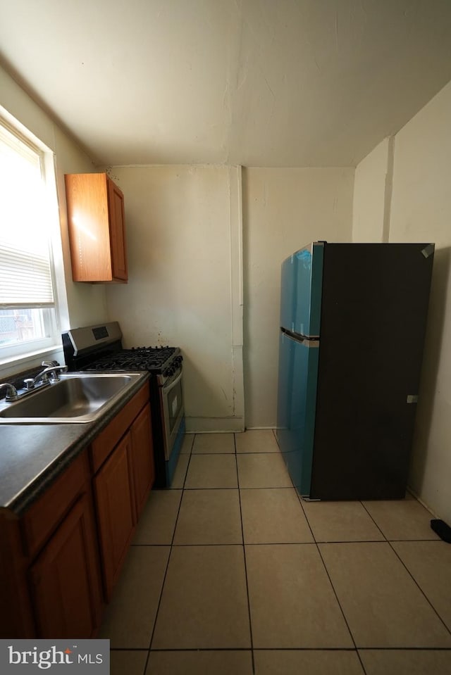 kitchen with black fridge, sink, gas stove, and light tile patterned floors