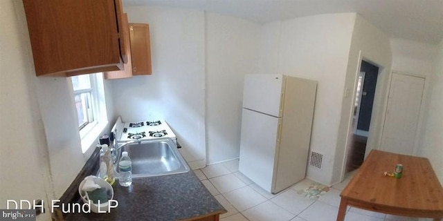 kitchen featuring sink, light tile patterned floors, and white fridge