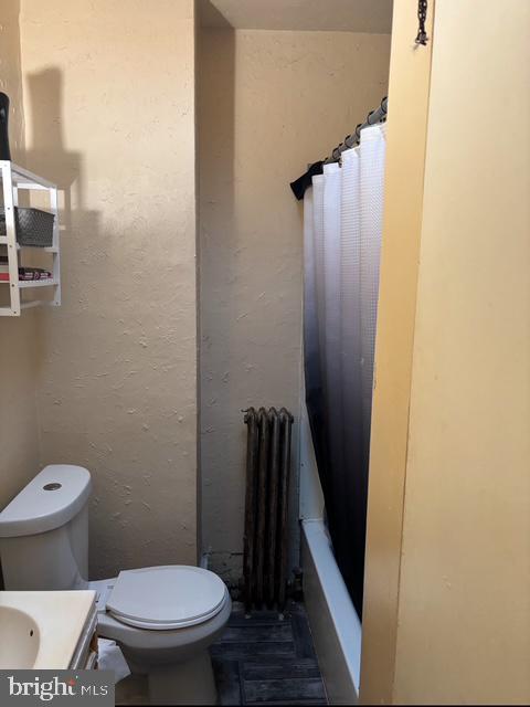 bathroom with vanity, radiator heating unit, and toilet