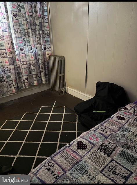 bedroom with concrete flooring and radiator heating unit