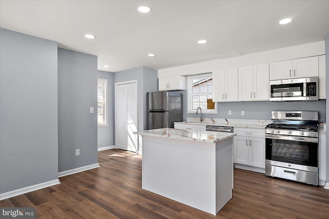 kitchen featuring white cabinets, stainless steel appliances, dark wood-style flooring, and a center island