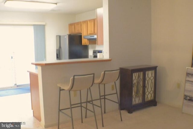 kitchen featuring stainless steel refrigerator with ice dispenser, plenty of natural light, a breakfast bar, and kitchen peninsula